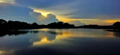 a large body of water with a sunset in the background at Tiny Island Lake Lodge in Bangkok