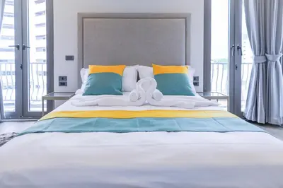 a bedroom with a large bed with yellow and blue pillows at Sukhumvit-Thonglor Luxury Pool Club Villa 5 Mins to BTS \u7d20\u5764\u9038-\u901a\u7f85 \u8c6a\u83ef\u6703\u6240\u6cf3\u6c60\u5225\u5885 5\u5206\u9418\u5230\u9054\u5730\u9435 in Bangkok