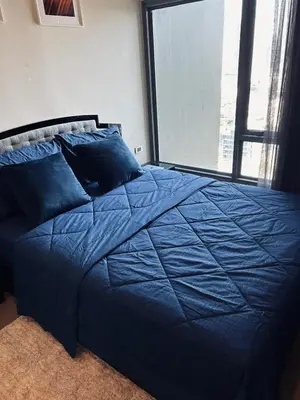 a blue bed in a bedroom with a large window at 1BR at Thonglor BTS InfinityPool overlooking city in Bangkok
