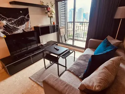 a living room with a couch and a tv and a table at 1BR at Thonglor BTS InfinityPool overlooking city in Bangkok