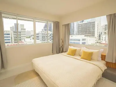 a bedroom with a white bed with a large window at Cozy 2-bedroom apartment in Silom city center - 6A in Bang Rak