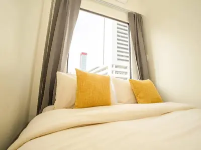 a bed with yellow pillows in front of a window at 2 Bedroom apartment at Silom with city center view - 5A in Bangkok