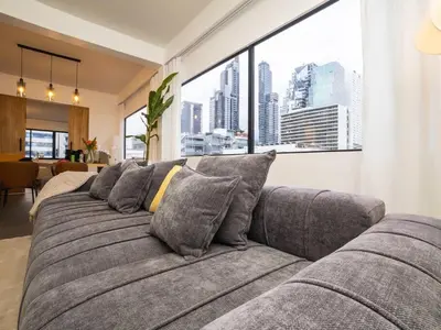 a large gray couch in a living room with windows at 2-Bedroom Penthouse in the heart of Silom - 4A in Bang Rak