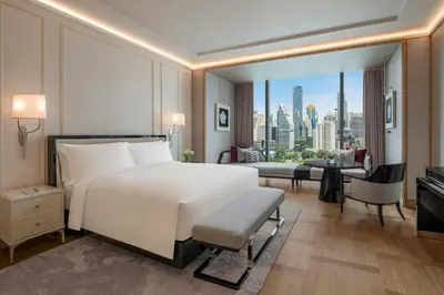 a bedroom with a white bed and a view of a city at The Ritz-Carlton, Bangkok in Bangkok