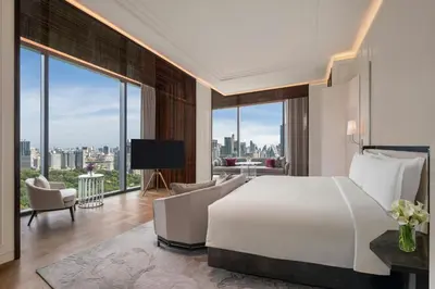 a bedroom with a large bed and a living room at The Ritz-Carlton, Bangkok in Bangkok