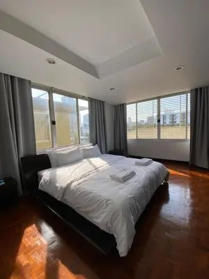 a bedroom with a large bed in a room with windows at Phatana Court in Bangkok