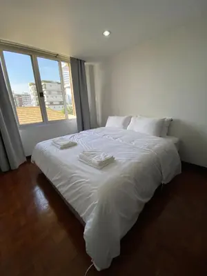 a white bed in a room with a large window at Phatana Court in Bangkok
