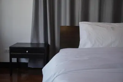 a bedroom with a white bed and a night stand at Phatana Court in Bangkok