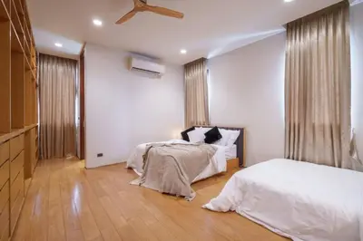 a bedroom with two beds with white sheets and a cat sitting on them at Ekkamai Villa Sleeps 12 with Cinema in Bangkok