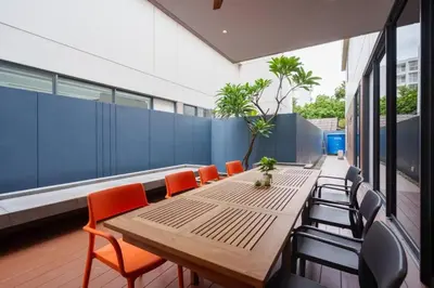 a long wooden table and chairs on a balcony at Ekkamai Villa Sleeps 12 with Cinema in Bangkok