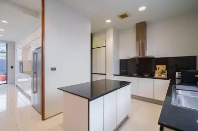 a kitchen with white cabinets and a black counter top at Ekkamai Villa Sleeps 12 with Cinema in Bangkok