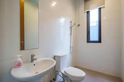 a bathroom with a sink and a toilet and a mirror at Ekkamai Villa Sleeps 12 with Cinema in Bangkok