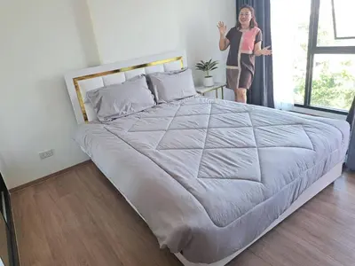a woman is standing next to a large bed at Cybiq Ratchada 32 by Pikul in Bangkok