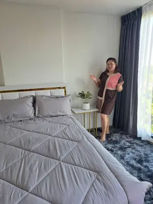a woman standing next to a bed in a bedroom at Cybiq Ratchada 32 by Pikul in Bangkok