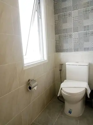 a bathroom with a white toilet with a window at Wellness World Chiva 89 in Ban Zong Katiam