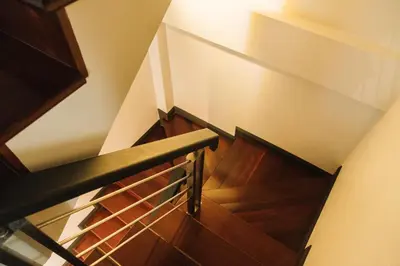 a wooden staircase with a metal rail and wood floors at My Sukhumvit Villa in Bangkok