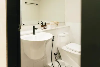 a white bathroom with a sink and a toilet at My Sukhumvit Villa in Bangkok