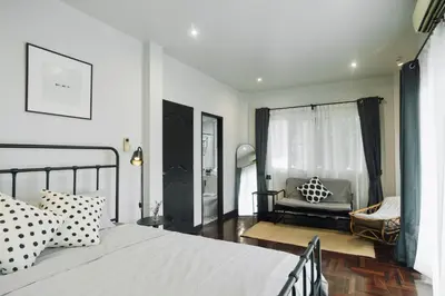a bedroom with a bed and a living room with a couch at My Sukhumvit Villa in Bangkok