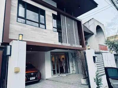 two people standing outside of a house with a car at Ekkamai\u4e09\u5367\u4e09\u536b\u5c0f\u522b\u5885\u72ec\u680b\u5e26\u505c\u8f66\u4f4d in Bangkok