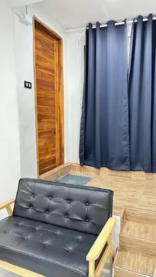 a living room with a black leather couch and a wooden door at Megun 10 L in Bangkok
