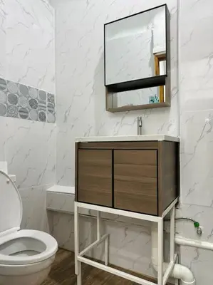 a bathroom with a sink and a toilet and a mirror at Megun 10 Duplex in Bangkok
