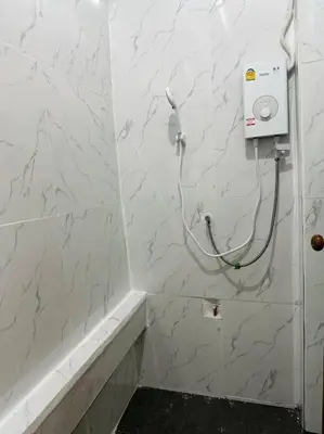 a white tiled bathroom with a hair dryer on the wall at Megun 10 Duplex in Bangkok