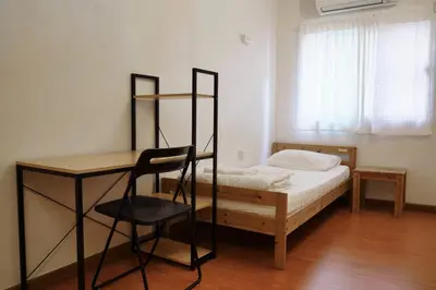 a bedroom with a bed and a desk and a chair at PanPan Hostel in Bangkok