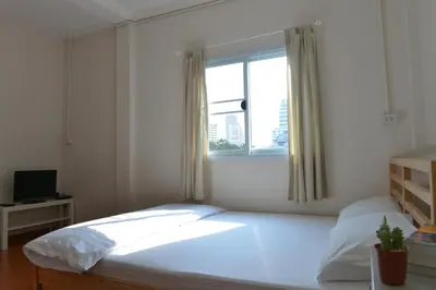 a bedroom with a large bed and a window at PanPan Hostel in Bangkok