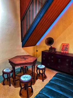 a living room with a table and stools and a staircase at The Courtesan at Yaowarat, townhome 80 Sqm in Samphanthawong