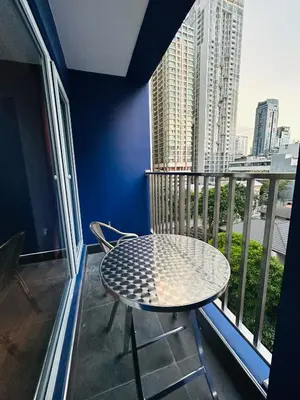 a table and chair on a balcony with a view of a city at Emiri Hotel - Nana Bangkok in Bangkok