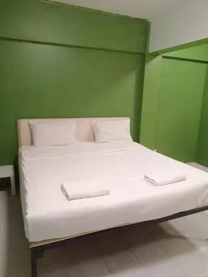 a bed with two white pillows and a green wall at z GO INN The Grand Palace Bangkok-Mrt Samyot Station in Bangkok