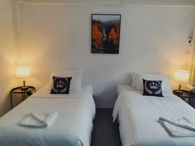 two beds in a room with a picture on the wall at ONEWAY Guest House BKK in Bangkok