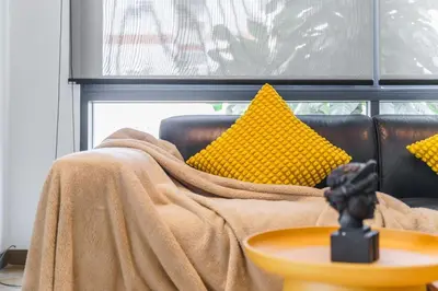 a couch with a blanket on it with yellow pillows at The Designer 49 Villa in Bangkok