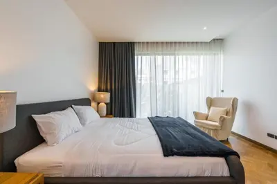 a bedroom with a bed and a chair and a window at The Designer 49 Villa in Bangkok