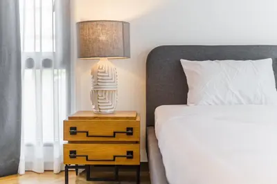 a lamp on a night stand next to a bed at The Designer 49 Villa in Bangkok