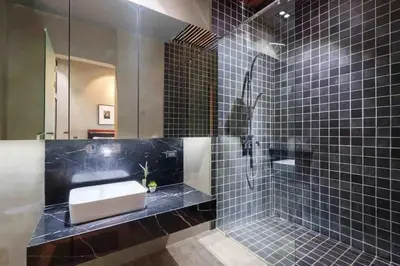 a black tiled bathroom with a sink and a mirror at The Oasis Tranquil Escape in Bangkok