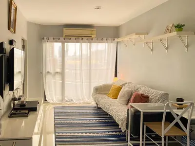 a living room with a couch and a window at Cozy 1br walk to BTS and Airport Rail Link Close to Malls 11 in Bangkok