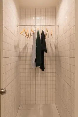 a bathroom with white tiled walls and racks of clothes at Samyan Story Boutique Hotel in Bangkok