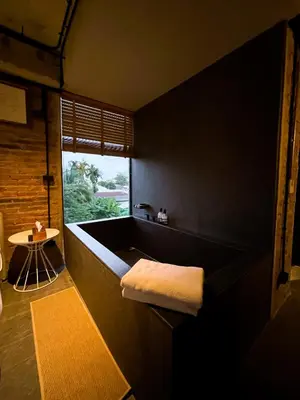 a bath tub in a room with a window at Cataleya Estate Boutique Bed & Breakfast in Bangkok