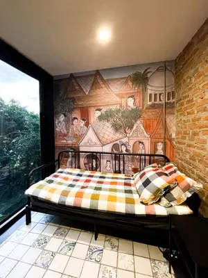 a bedroom with a bed with a mural on the wall at Cataleya Estate Boutique Bed & Breakfast in Bangkok