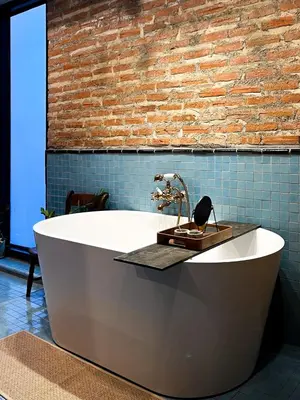 a white bath tub in a room with a brick wall at Cataleya Estate Boutique Bed & Breakfast in Bangkok