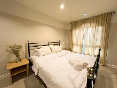 a bedroom with a bed with white sheets and a window at Vanilla house in Nonthaburi