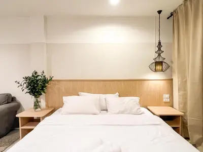 a bedroom with a white bed and a couch at Vanilla house in Nonthaburi