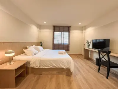 a bedroom with a bed and a desk and a television at Vanilla house in Nonthaburi