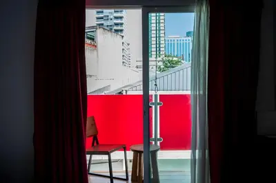 a room with a window with a red wall and a chair at Elite Hotel Asok Sukhumvit 20 in Bangkok