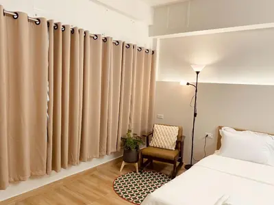 a bedroom with beige curtains and a chair at Cozy Corner Bangpho in Bang Su