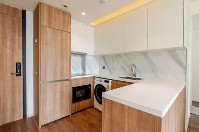 a kitchen with white cabinets and a washer and dryer at Pet Friendly Modern Nest Asoke in Bangkok