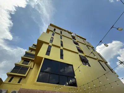 a tall yellow building with a blue sky in the background at Breezewood Bangkok Hotel in Bang Su