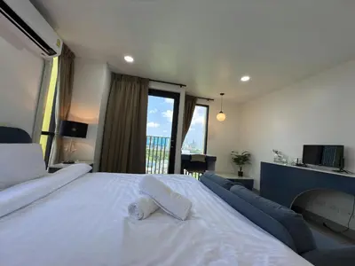 a bedroom with a large white bed and a balcony at Breezewood Bangkok Hotel in Bang Su