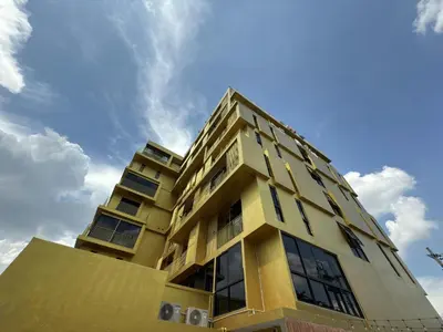 a yellow building with a sky in the background at Breezewood Bangkok Hotel in Bang Su
